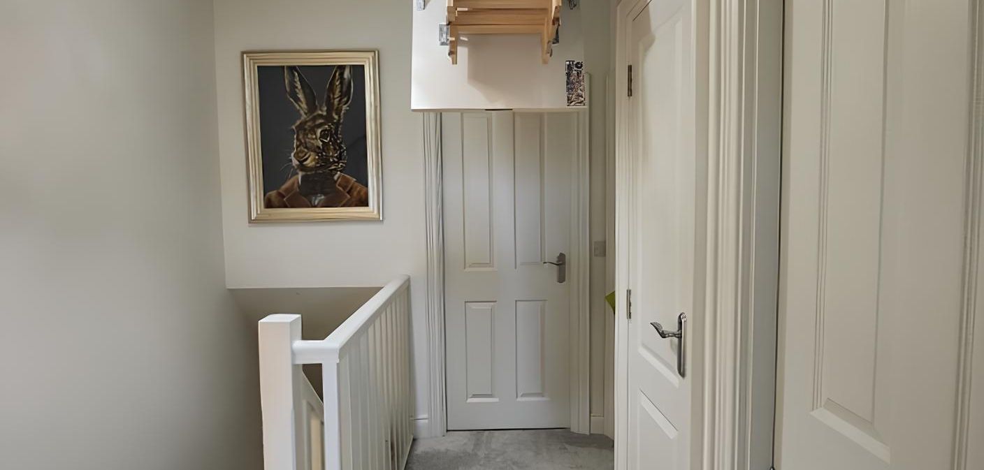 Hallway with a painting of a rabbit, white doors, and a staircase.