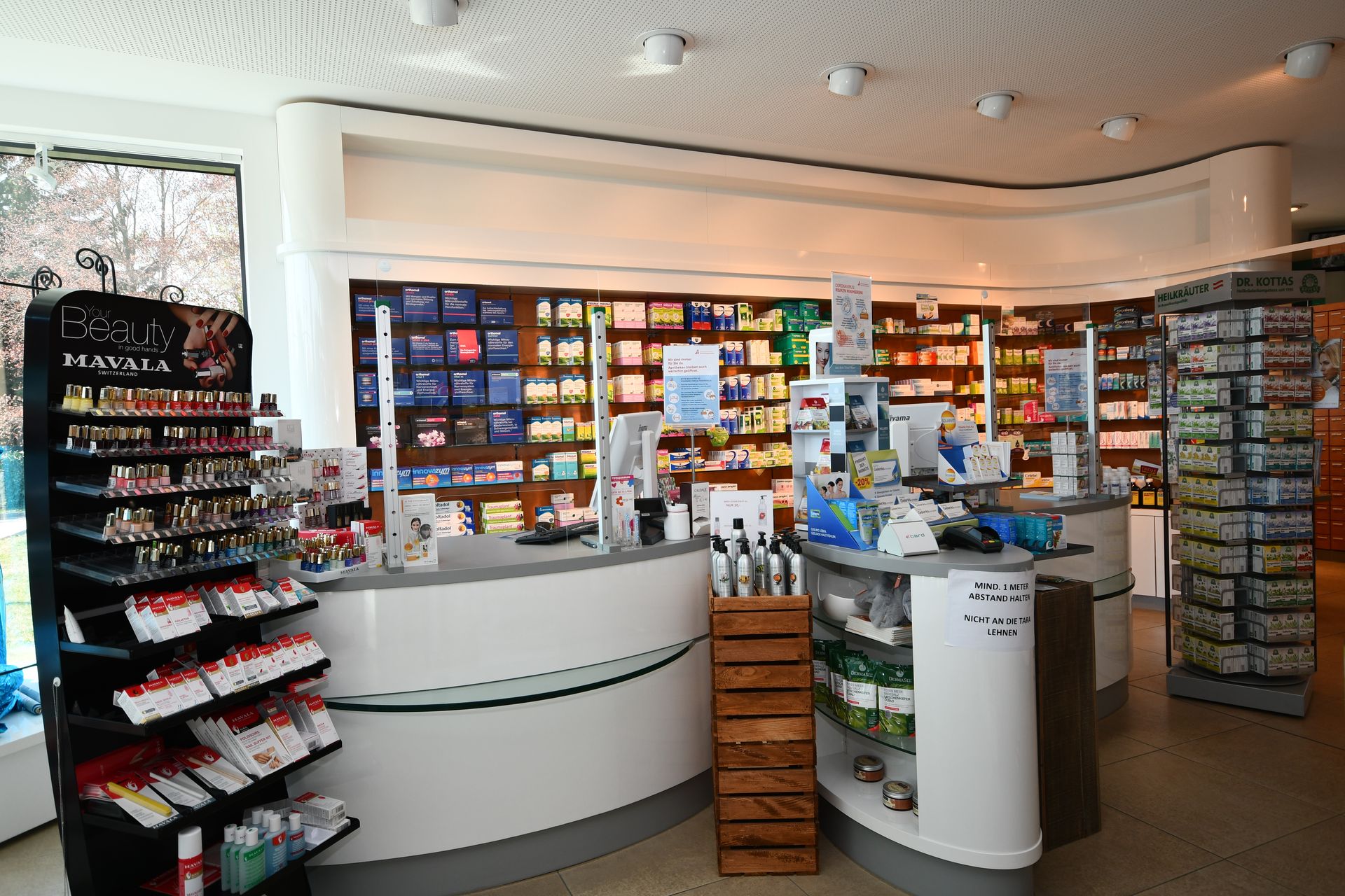 Innenansicht einer Apotheke mit Regalen voller Produkte und einem geschwungenen Tresen.