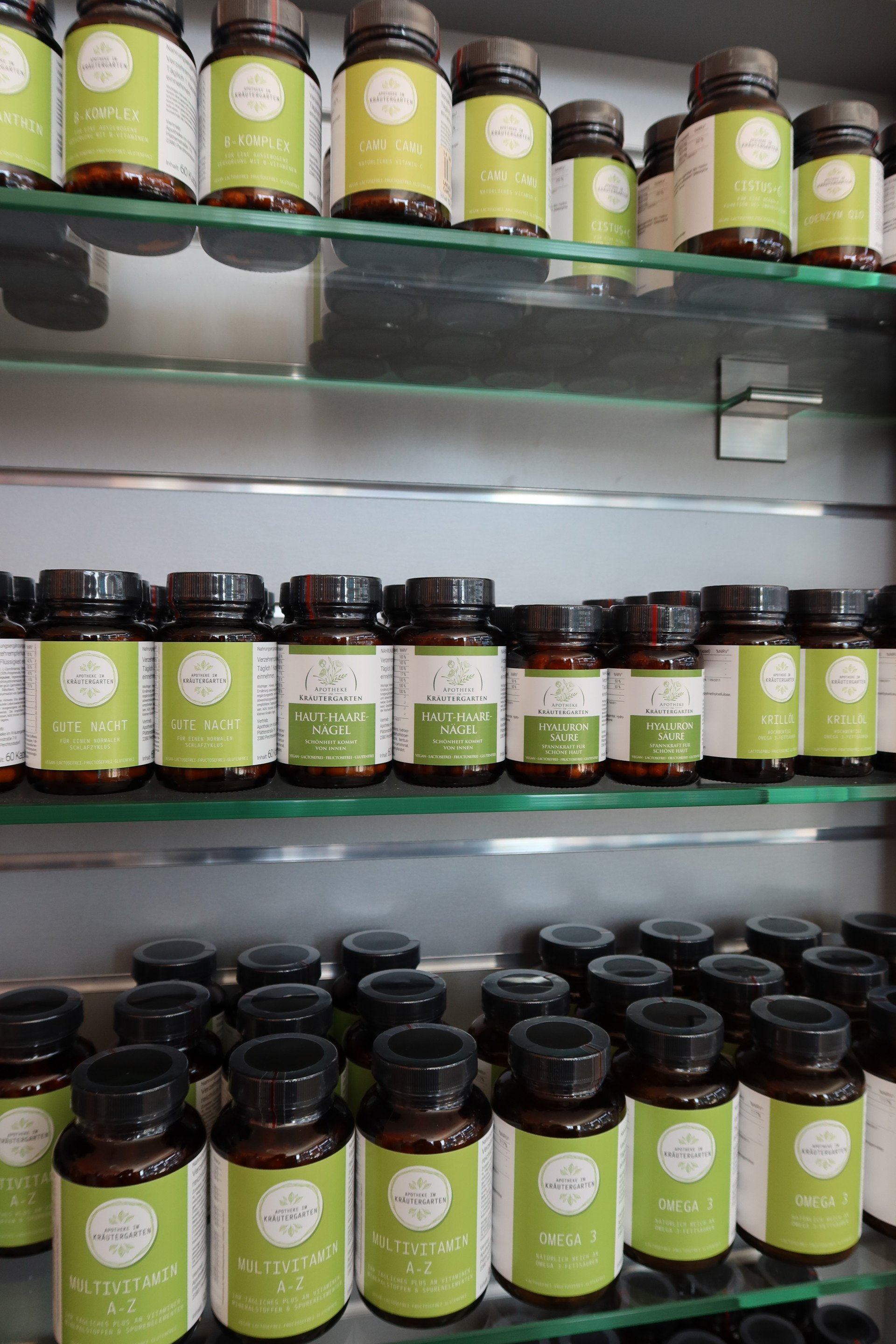 Regale voller brauner Flaschen mit Nahrungsergänzungsmitteln und grünen und weißen Etiketten.