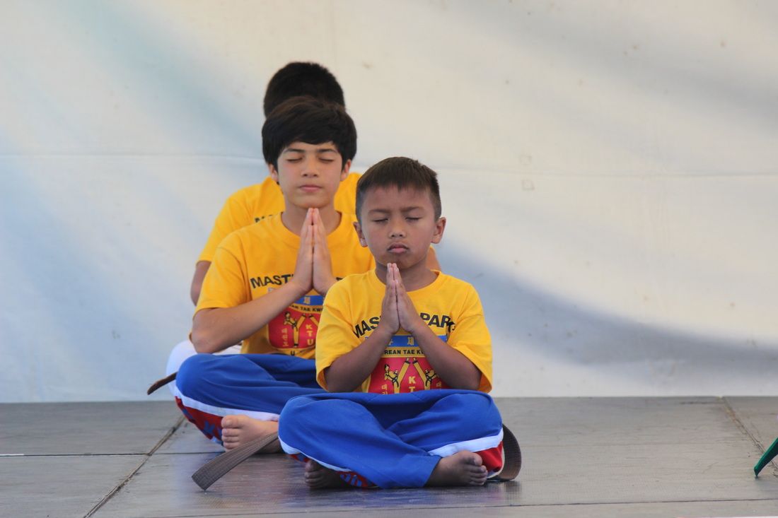 A group of young boys sit in a lotus position with their hands folded