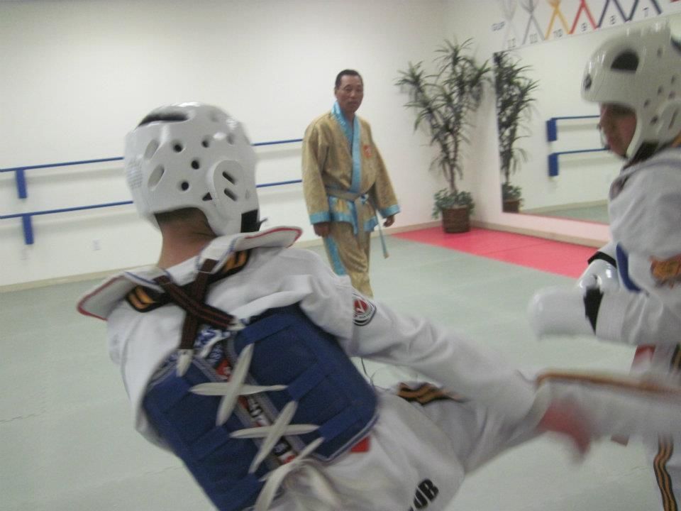 A man in a blue robe is watching two karate fighters