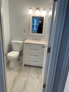Small bathroom with white vanity, toilet, mirror, and blue door trim