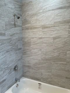 Modern bathroom shower and tub with gray tiled walls and chrome fixtures
