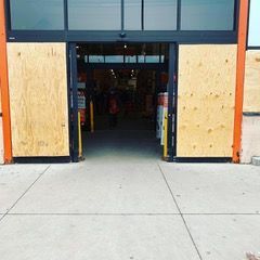Boarded storefront entrance with plywood over windows and open doorway