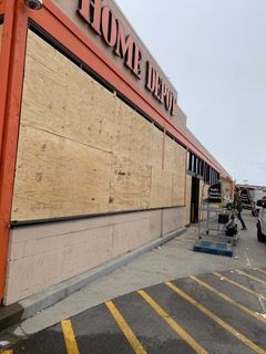 Boarded storefront with plywood over windows, red trim, and yellow parking lines in front