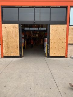 Storefront entrance boarded with plywood, orange frame, and open doorway leading inside