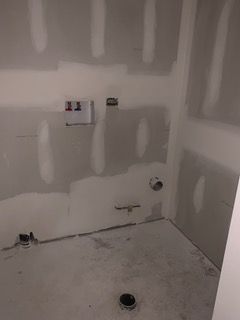 Unfinished bathroom with drywall, plumbing outlets, and a bare concrete floor under renovation