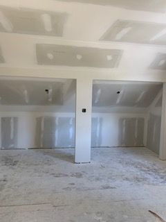 Unfinished interior room with drywall, exposed seams, and concrete floor under construction