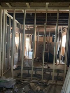 Unfinished room framed with exposed wooden studs and rubble on the floor