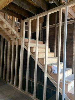 Unfinished wooden staircase with exposed studs in a construction area