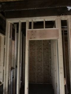 Unfinished interior framing of a narrow doorway or hallway with exposed studs and insulation