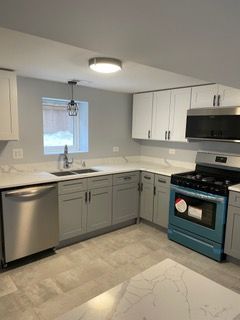 Modern kitchen with gray cabinets, stainless steel appliances, and a window above the sink