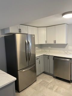 Modern kitchen with stainless steel appliances, white cabinets, and light countertops
