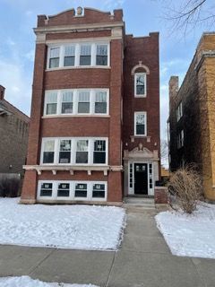 Red brick apartment building with snow-covered sidewalk and a narrow side entrance
