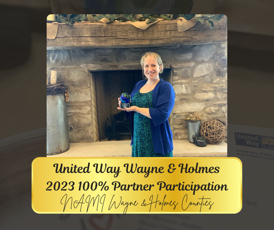 Woman holding trophy in front of a stone fireplace, celebrating 100% partner participation.