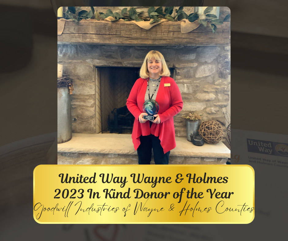 A woman in a red blazer holds an award in front of a fireplace. Award reads 