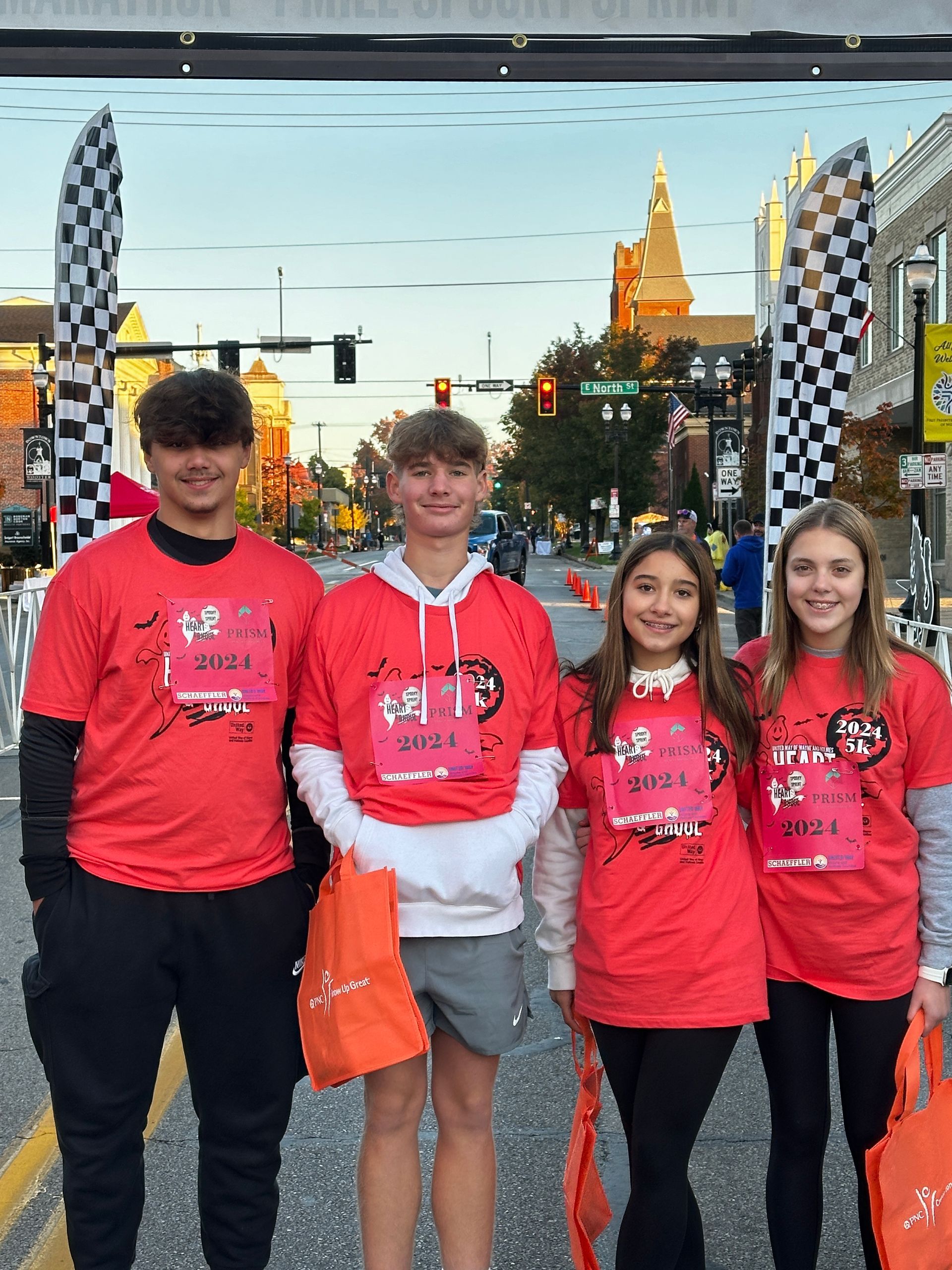 Four people in red shirts at a race, standing near the finish line.