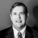 Man in suit and tie smiling, headshot.