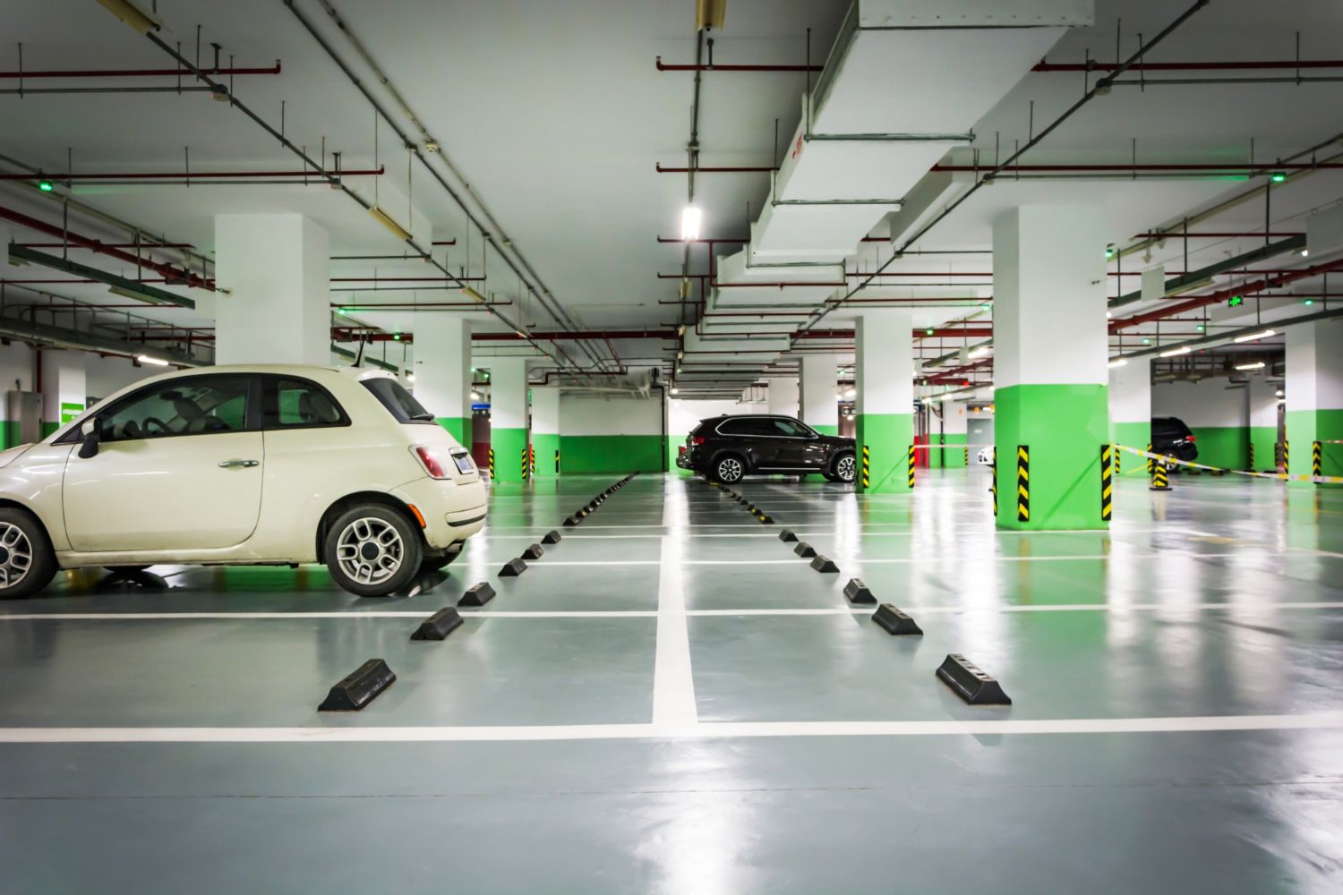 Underground parking garage with white and black cars parked in marked spaces.