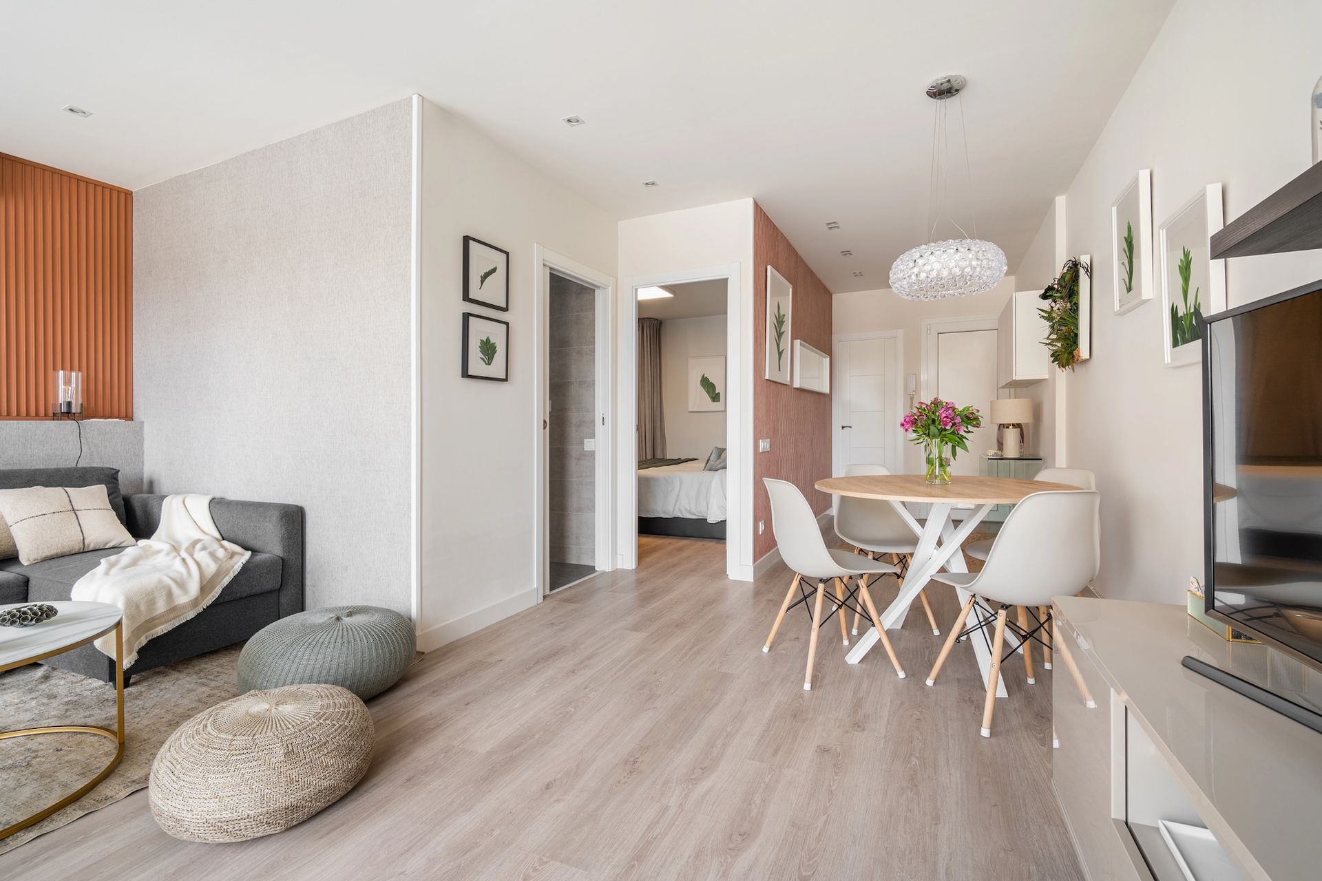 Living room with sofa, table, and chairs; light wood floors, peach and white walls.