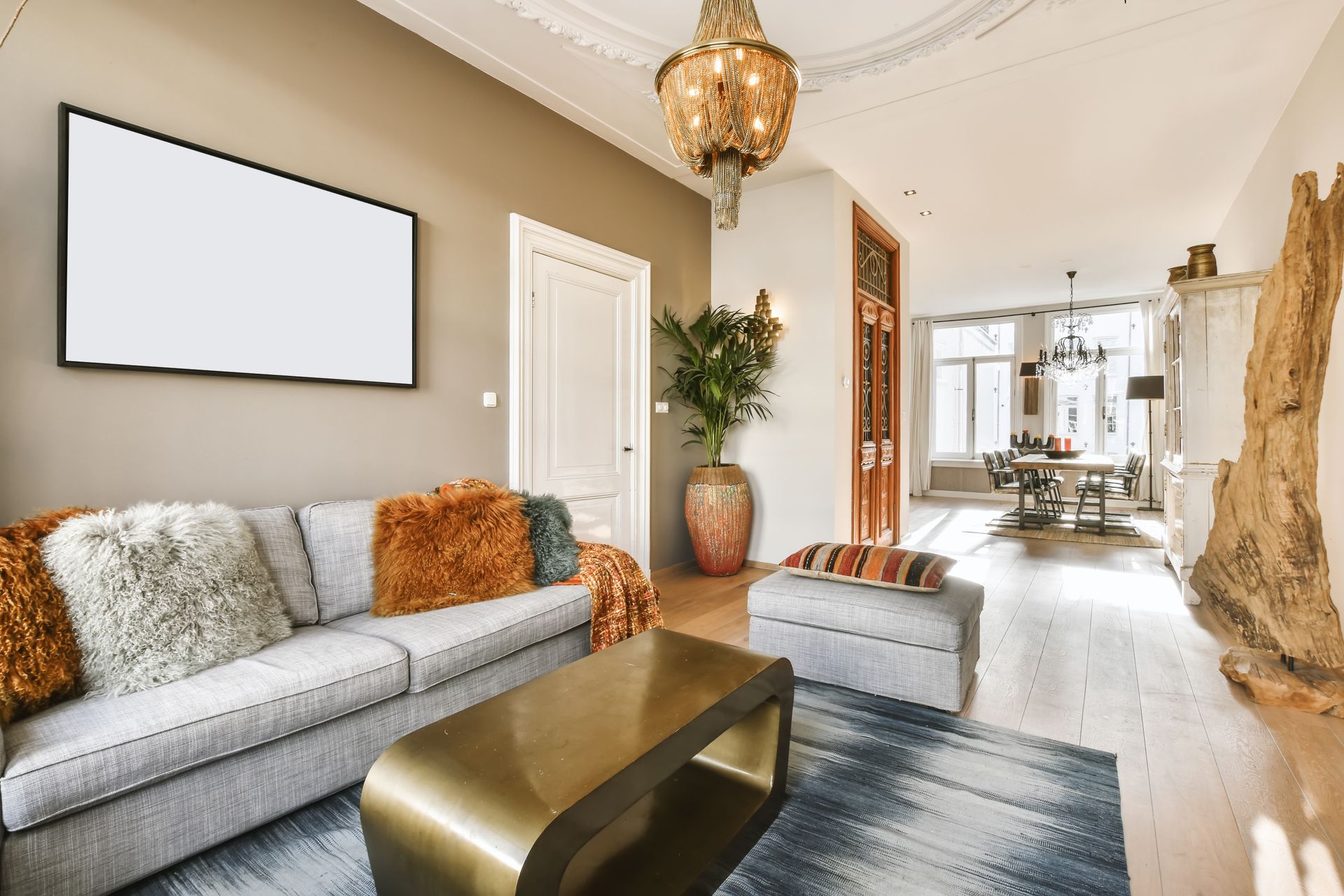 Living room with gray sofa, gold coffee table, and blank TV screen on a beige wall.