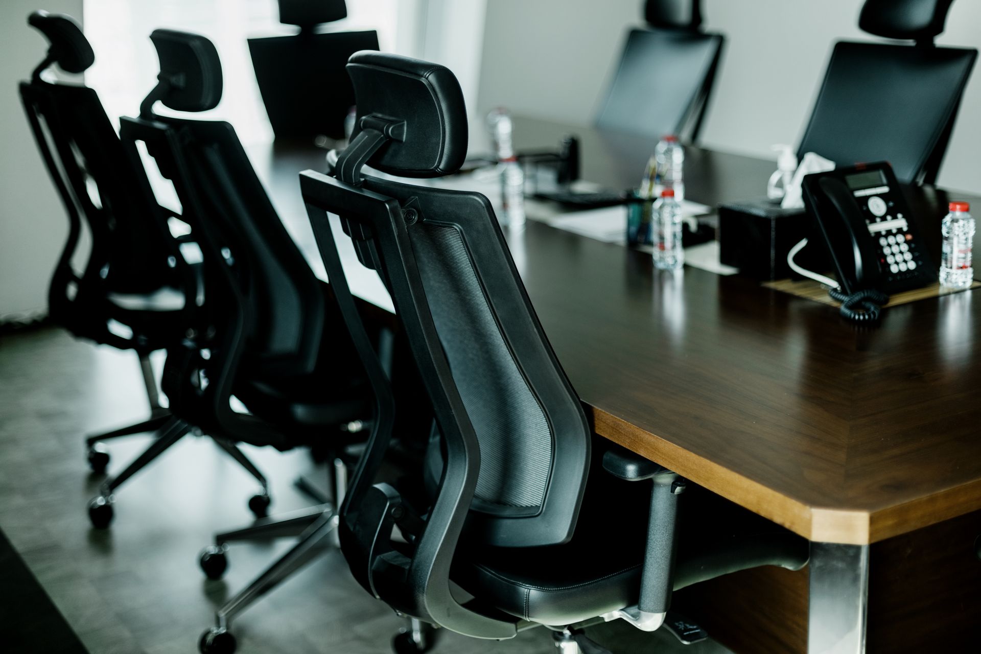 Conference room with black chairs and a brown table.