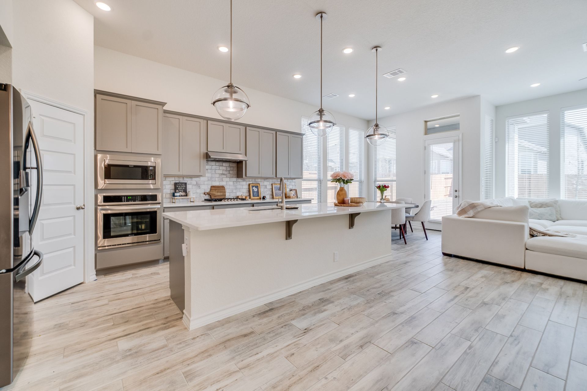 Open-concept kitchen with large island, stainless steel appliances, and white cabinets.