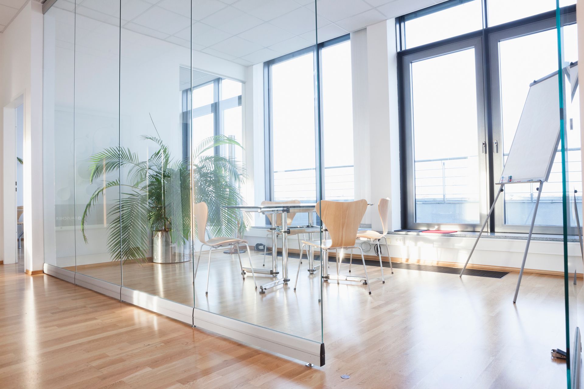 Bright, modern office space with glass walls, hardwood floors, and a conference table.