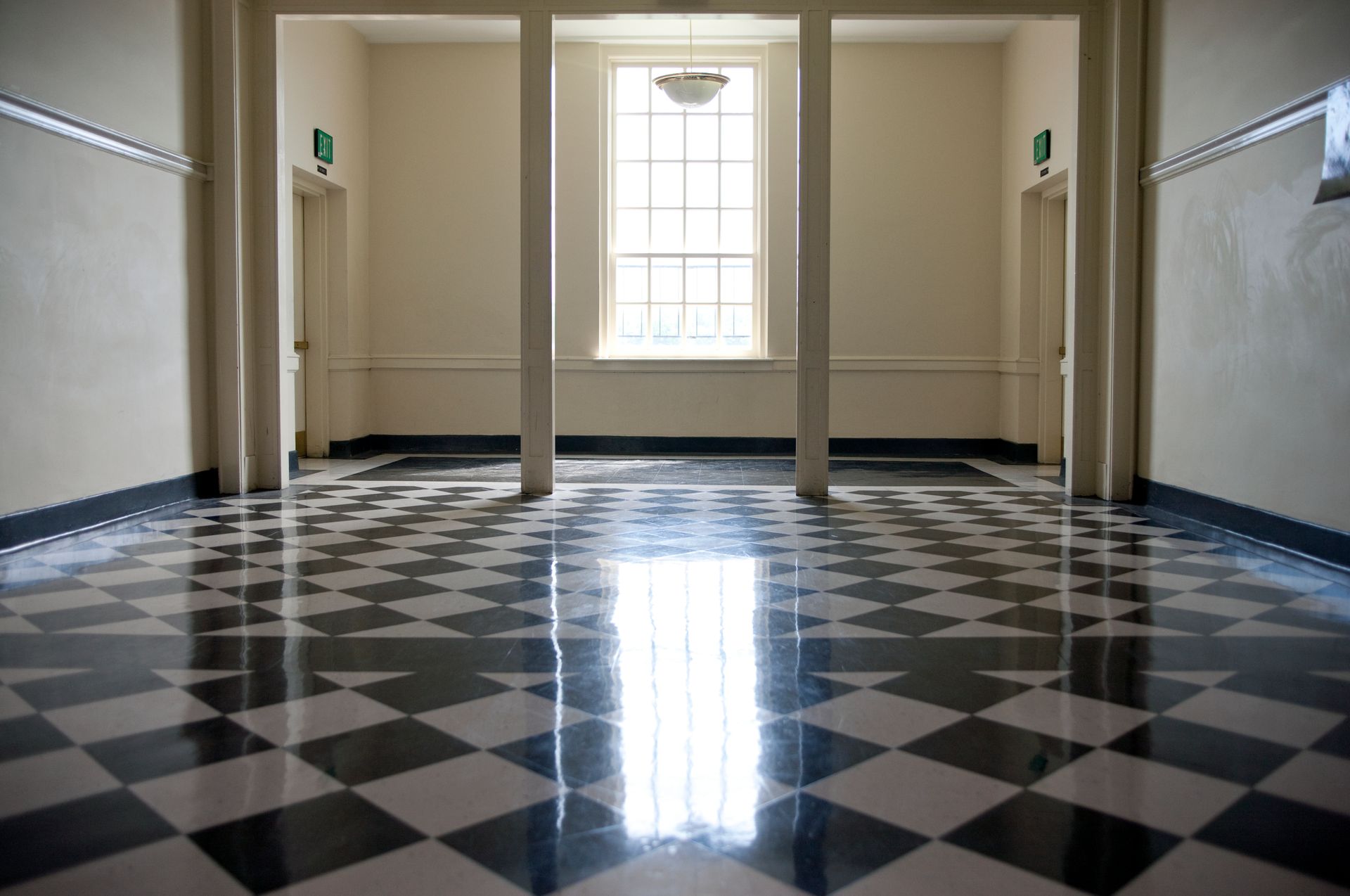 Hallway with black and white checkered floor, three columns, window, and two doors.