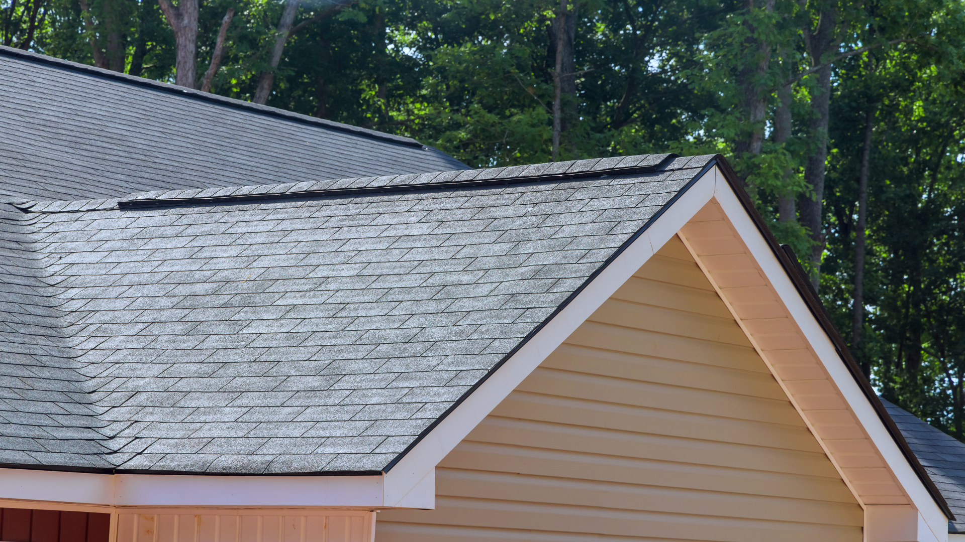 Gray shingled roof with a tan gable against green trees