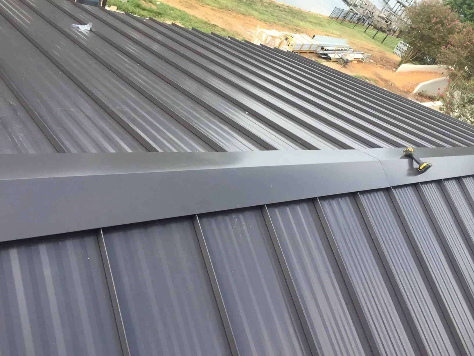 Dark corrugated metal roof with a ridge cap, viewed from above on a sloped building.