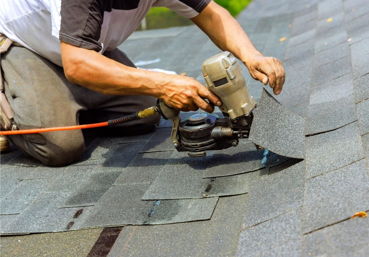Worker aligning dark roof shingles during roof repair