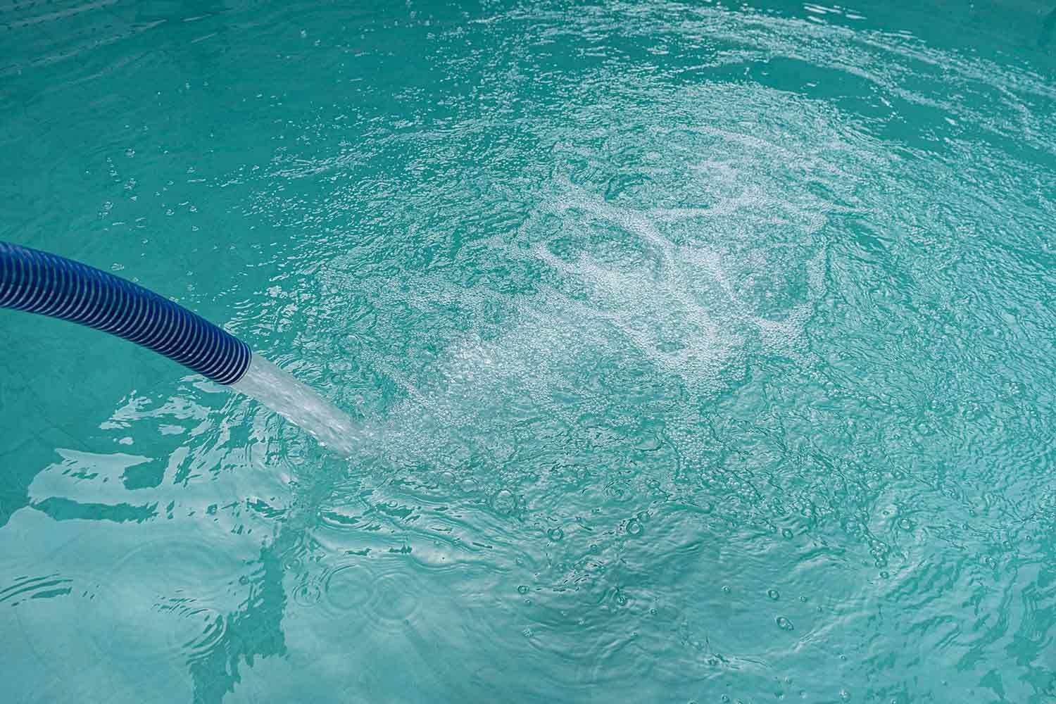 A Blue Hose is Spraying Water Into a Swimming Pool — Hinterland Water Cartage in Mooloolah Valley, QLD