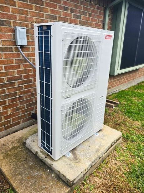 Outdoor HVAC unit beside a brick house wall on a concrete pad