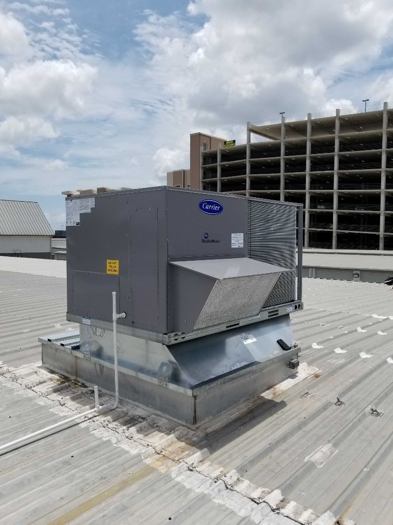 Roof-mounted HVAC unit on a commercial building under a cloudy sky.