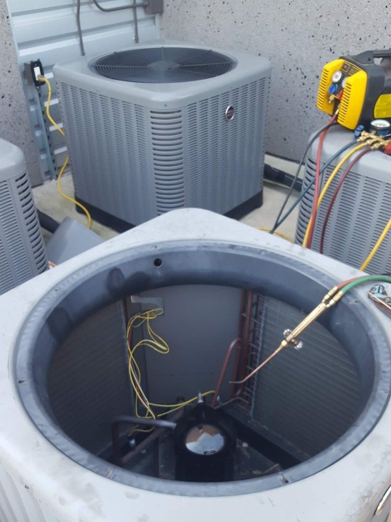 Open HVAC units on a rooftop, with exposed wiring and tools visible.