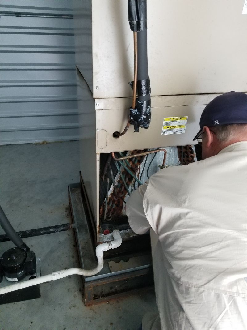 Technician repairing wiring inside an industrial HVAC unit, with tools and exposed cables.
