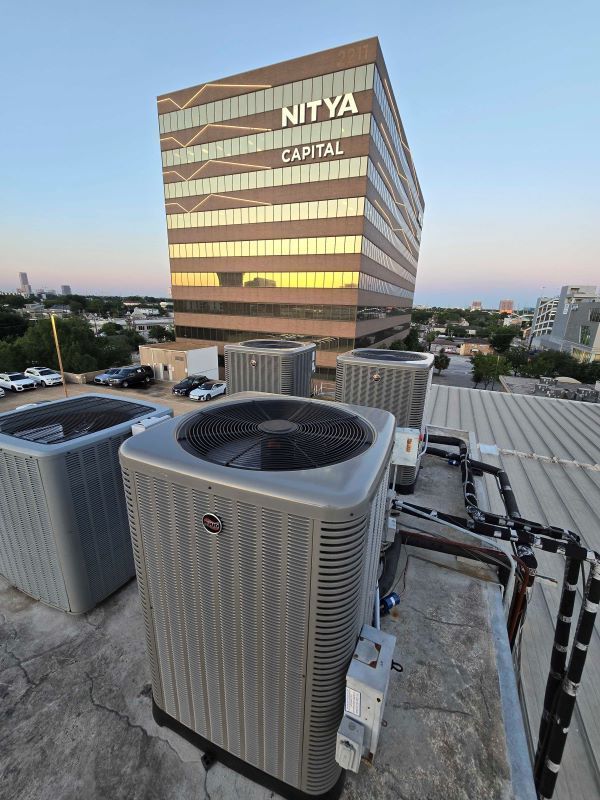Rooftop HVAC units in foreground with a sunset-lit office tower