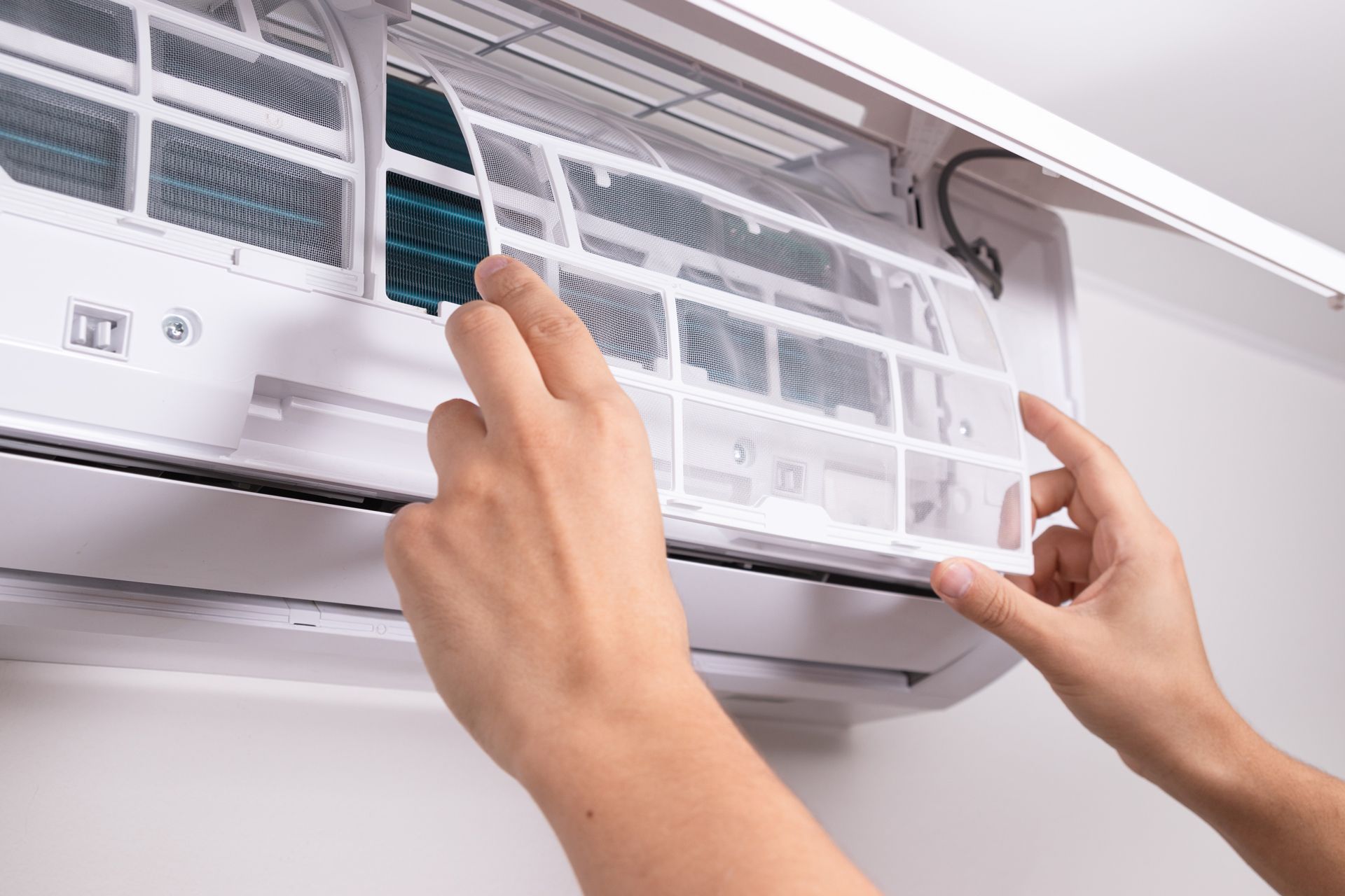 Hands removing an air conditioner filter for cleaning