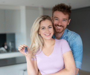 Couple smiling, holding keys; celebrating new home purchase.