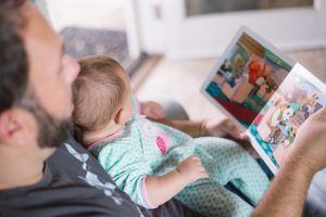 A person reading a picture book to a baby, indoors.
