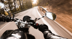 Motorcycle rider on a winding road through a forest, first-person perspective, blurred motion.