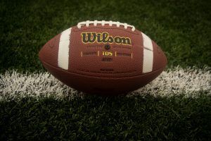 Brown Wilson football on a white line of a green grass field.