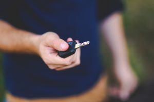 Hand holding out a car key.