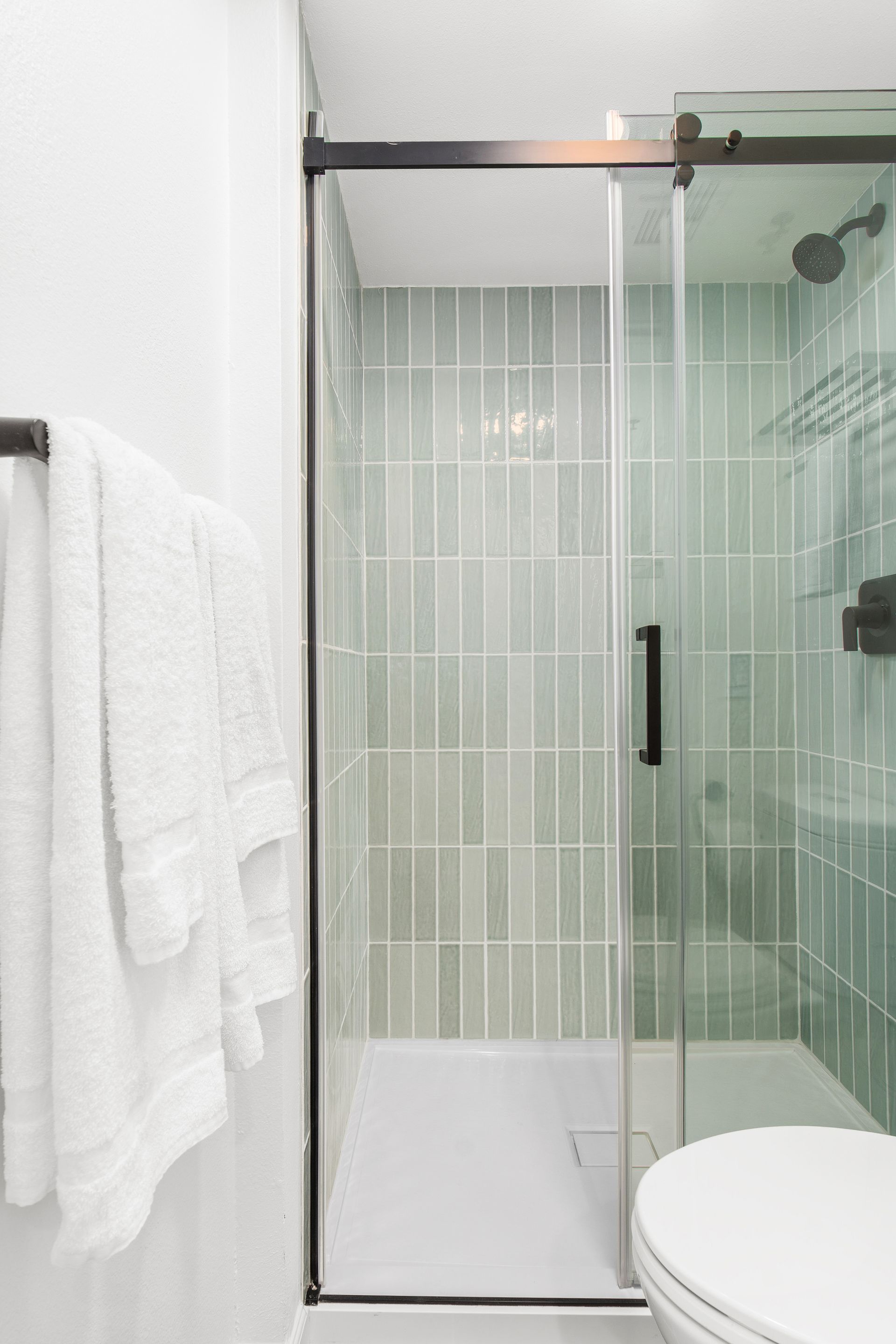 A bathroom with a toilet , shower , and towel rack.