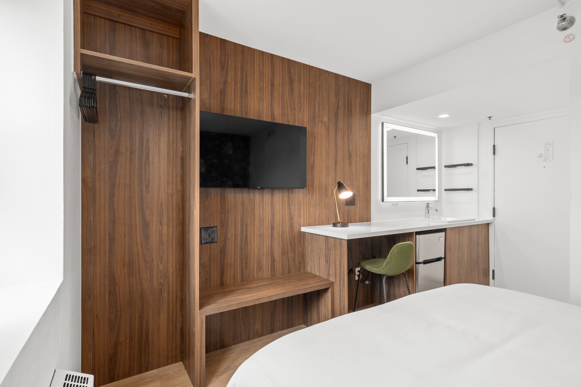 A hotel room with a bed , desk , television and mirror.