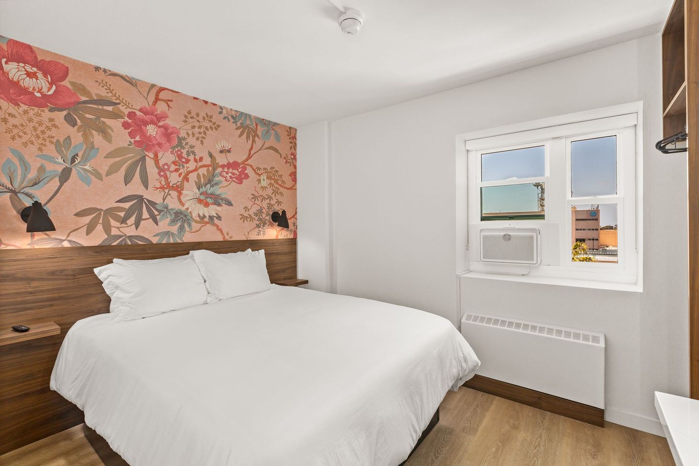 A hotel room with a king size bed and a window.
