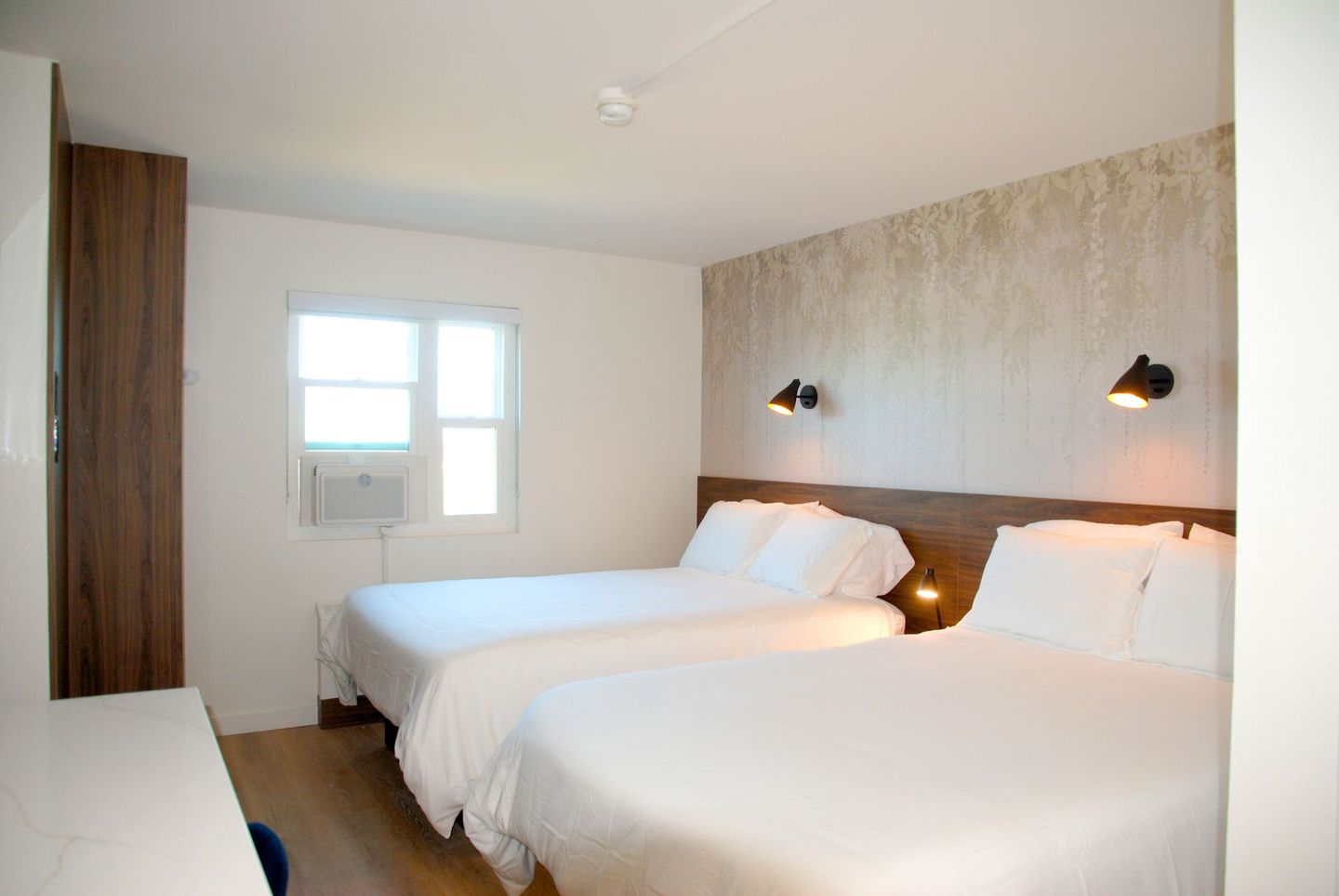 A hotel room with two beds and a window.