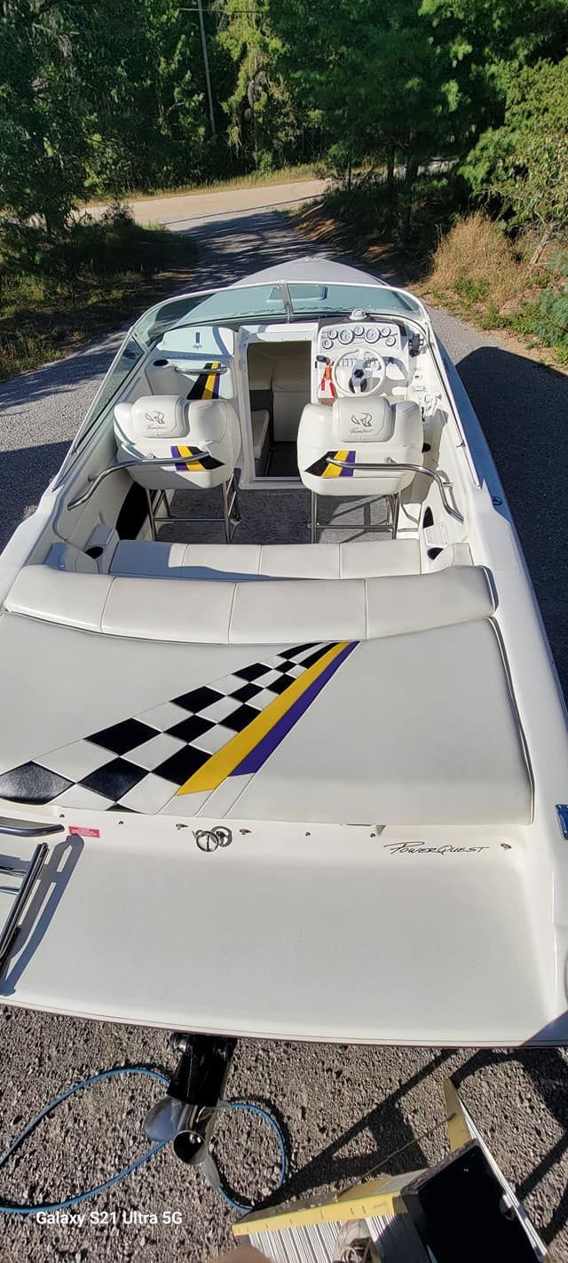 A white boat with a checkered flag on the back is parked on the side of the road.