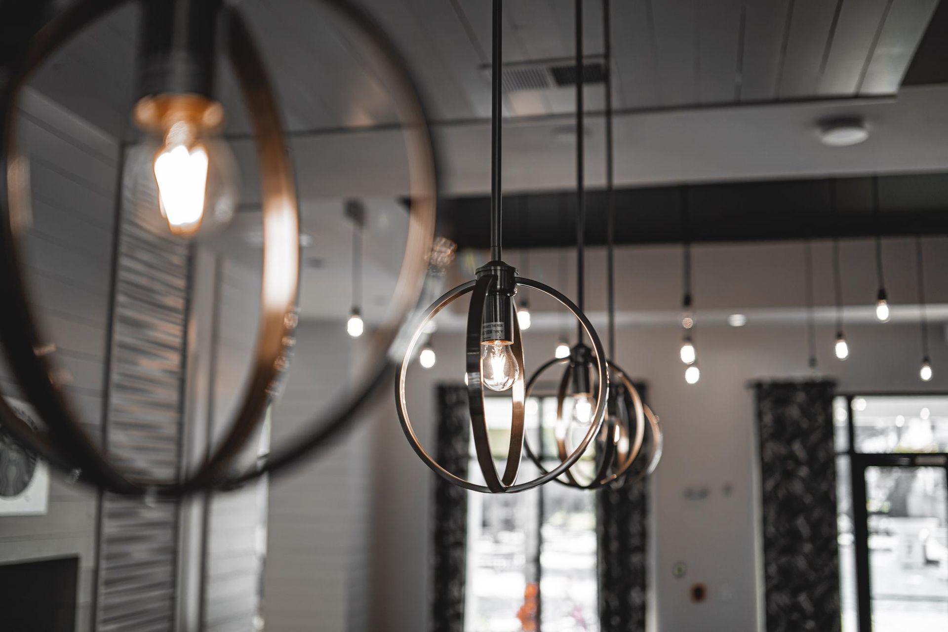 Modern pendant lights hanging in a sleek interior with black walls and windows
